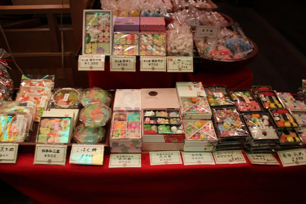 A display of colorful Japanese traditional sweets for sale, with price tags.