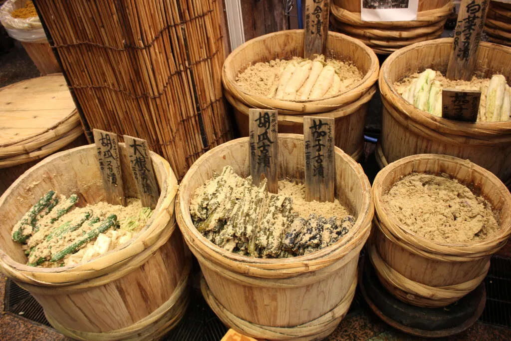 A variety of pickled vegetables displayed in wooden barrels at a market in Kyoto.