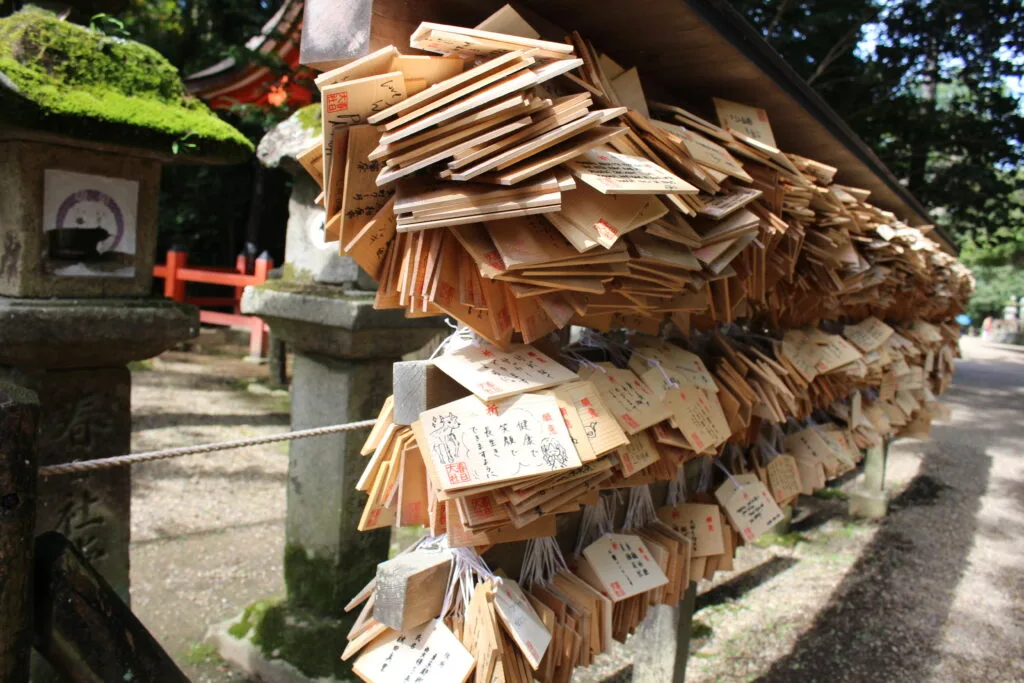 A collection of ema (wooden prayer plaques) tied to a stand at Fushimi Inari Taisha, where visitors write wishes and prayers.