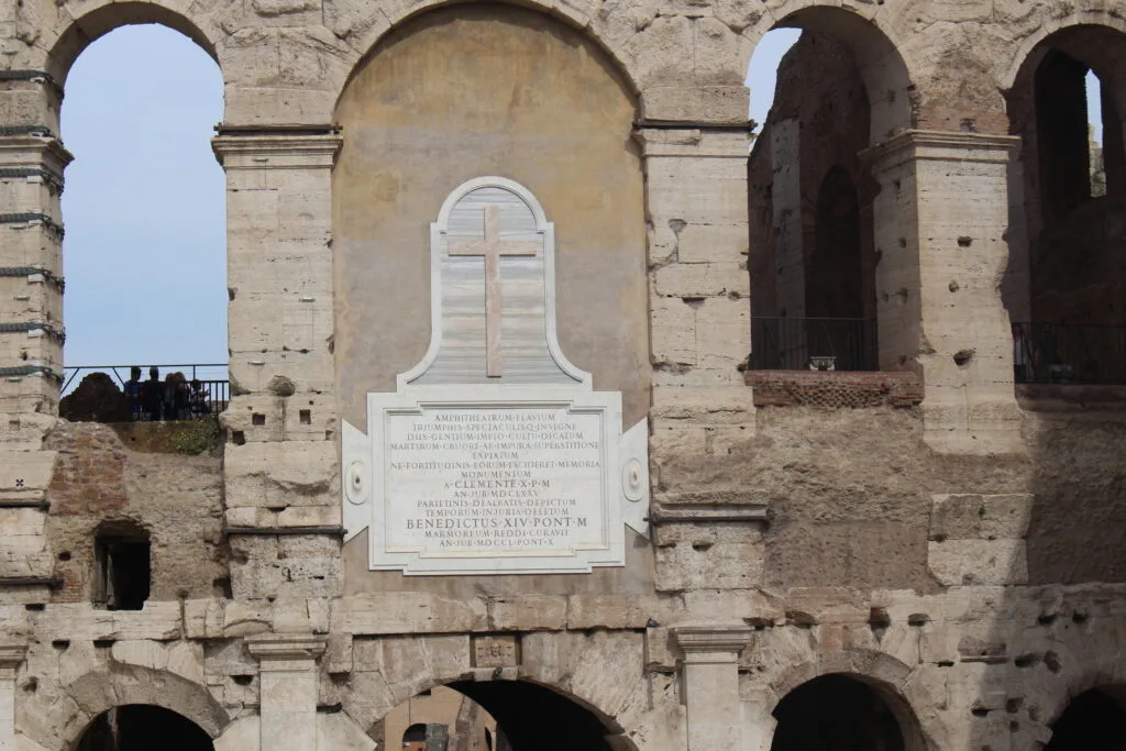 A close up view of a cross and inscription inside the Colosseum.