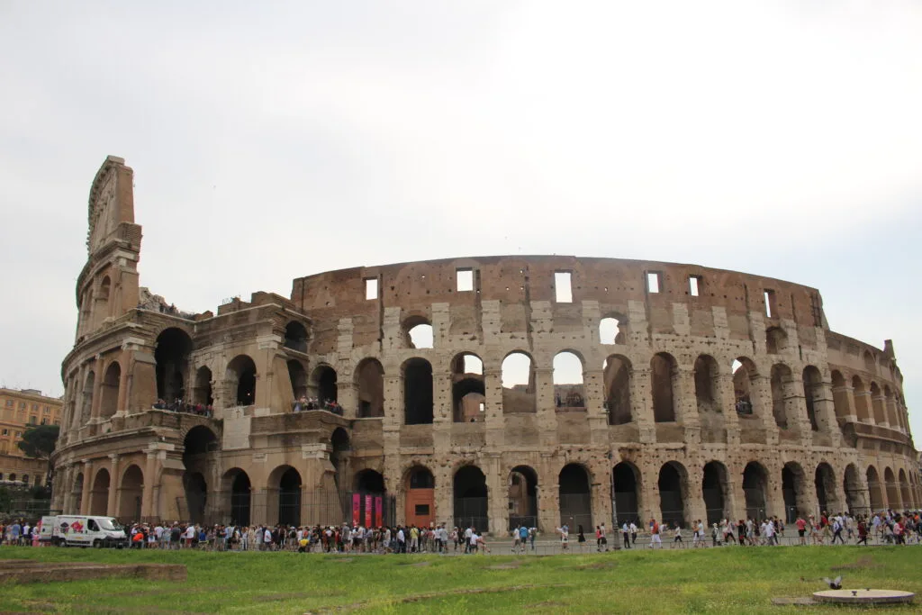 Exterior view of the Colosseum in Rome with tourists gathered outside.