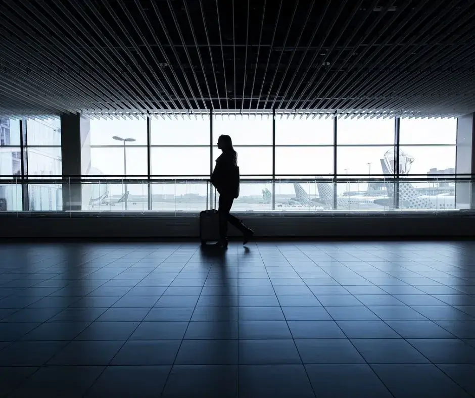 A person walking in an airport with luggage. Physical activity, even in the airport, can help you get sleep on the plane.