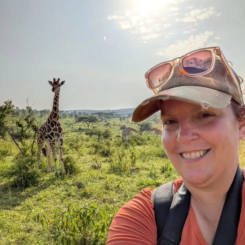 Pam posing for a selfie with a giraffe in Uganda